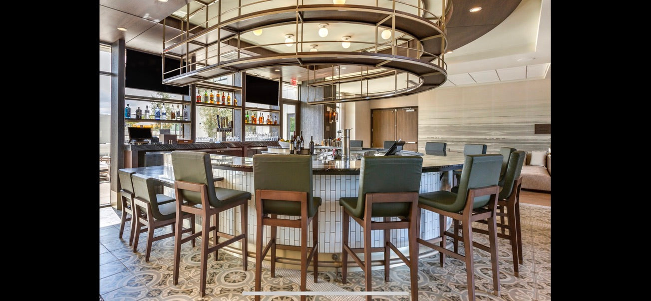 Dining area with a large round chandelier, table, and chairs in a modern interior setting.
