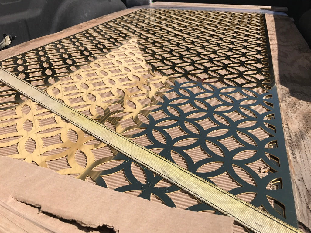 Metallic decorative screen with geometric pattern on a wooden surface