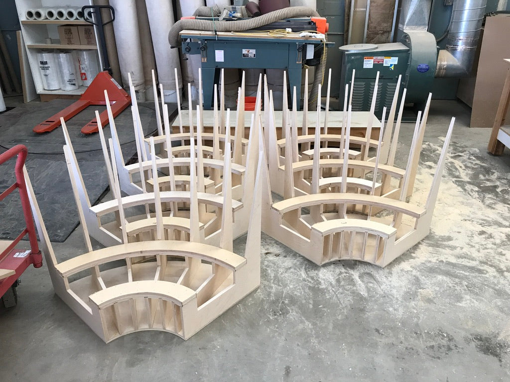 Wooden architectural model on a concrete floor with tools and materials in the background