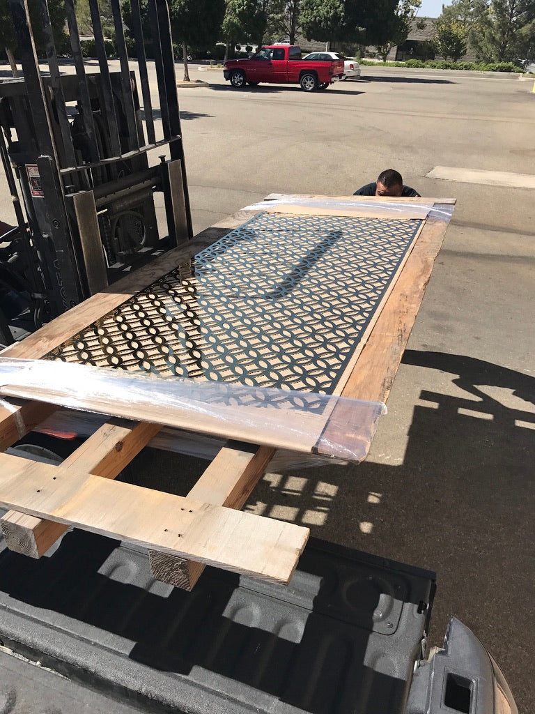 Wooden pallet with a large rectangular object on a forklift in an outdoor setting.
