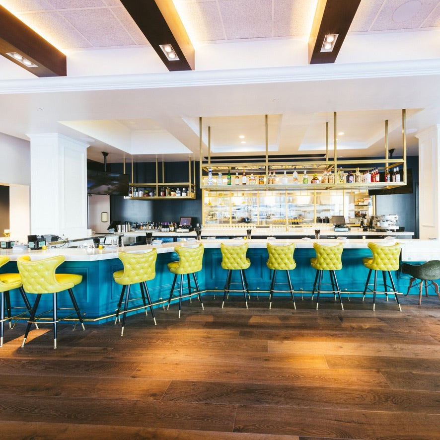 Modern bar with blue counter and yellow stools in a stylish interior.