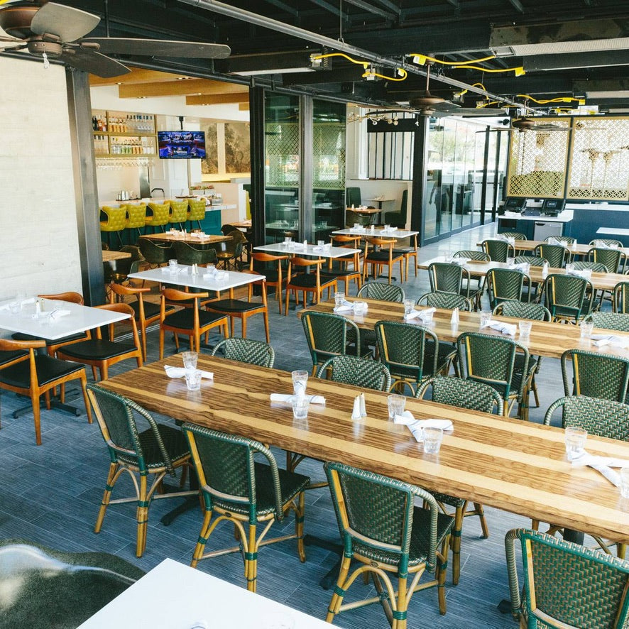 Restaurant interior with tables, chairs, and a TV on the wall.