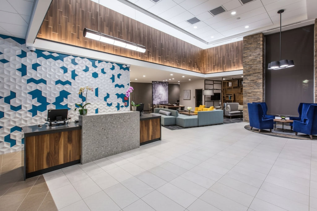 Modern hotel lobby with reception desk, seating area, and decorative wall.
